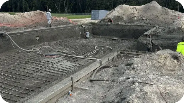 Workers finishing a concrete pool shell during construction.