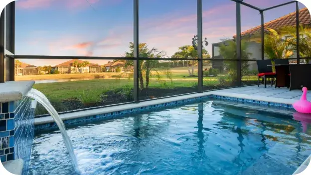 Screened lanai pool with a water-jet feature at dusk.