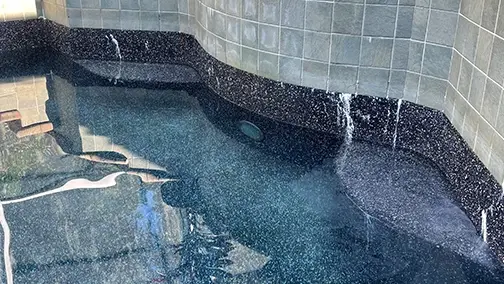 Water spilling over a dark tile waterfall wall.