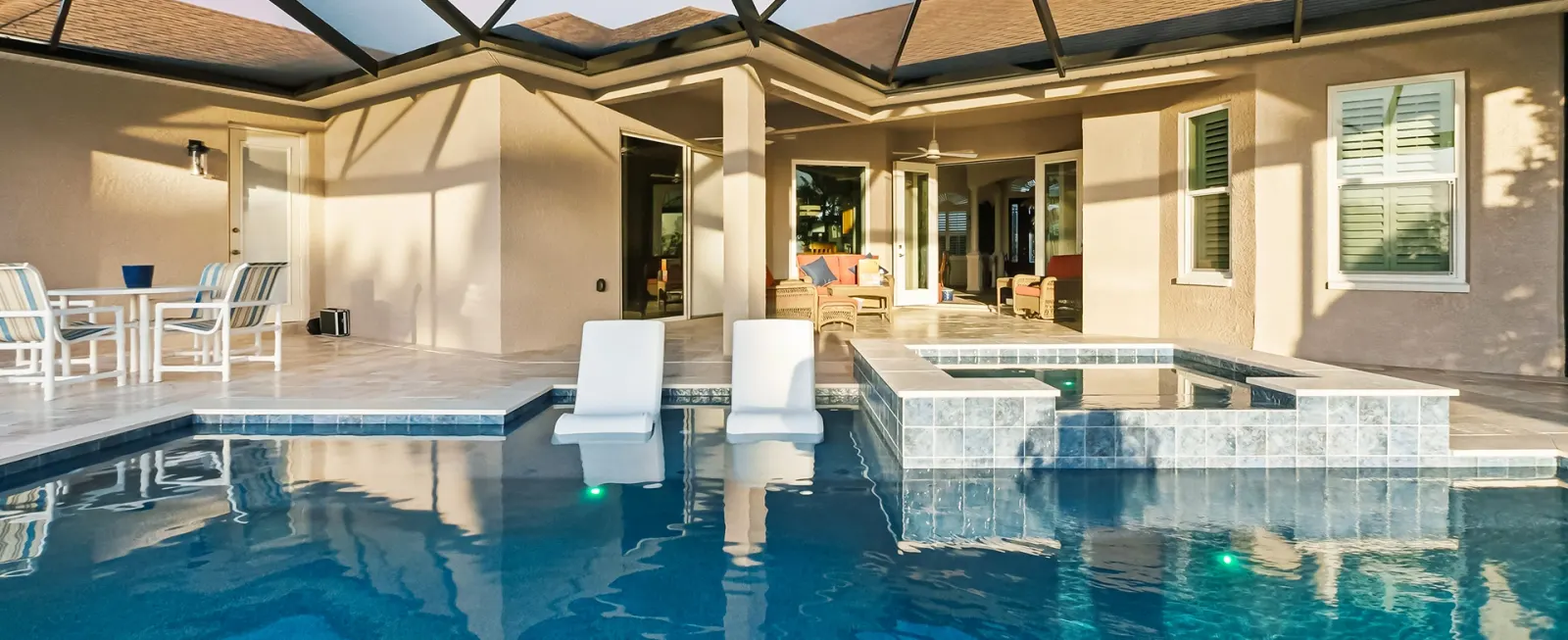 Screened lanai pool and spa with lounge chairs overlooking a golf course.