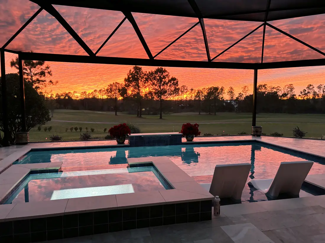 Raised spa and sun shelf beside the pool at sunset, golf course in the background.
