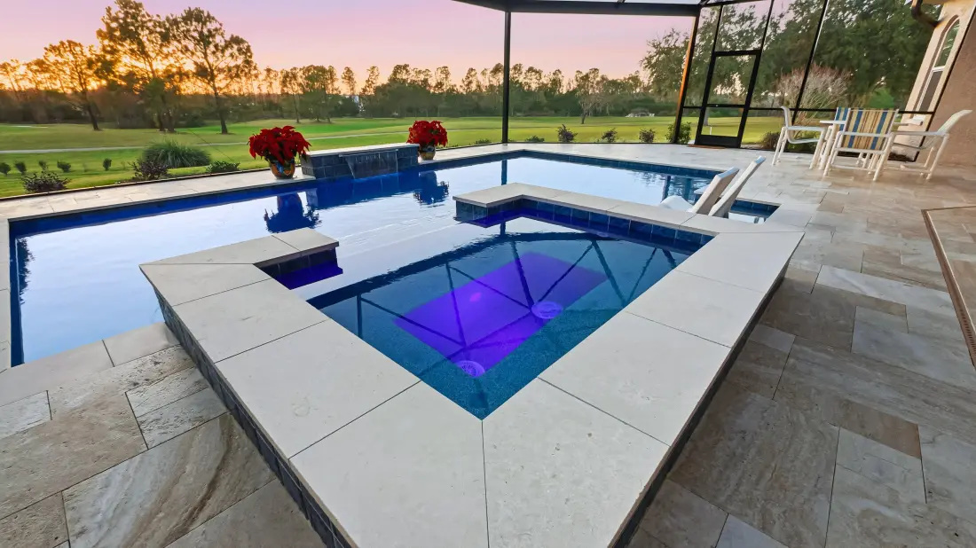 Raised square spa lit with purple LED lighting at dusk.