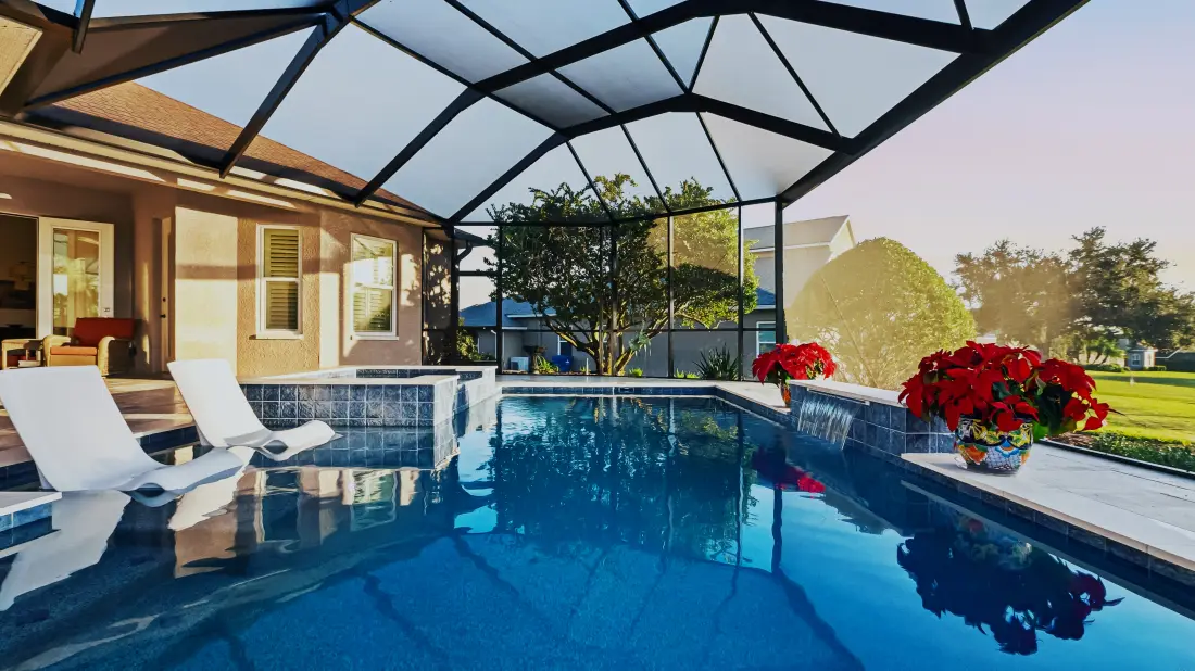 Pool and spa with lounge chairs inside a screened lanai, golf course at dusk.
