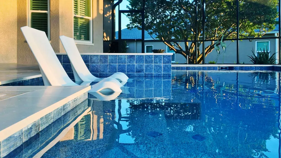 Two white lounge chairs on the pool's sun shelf.