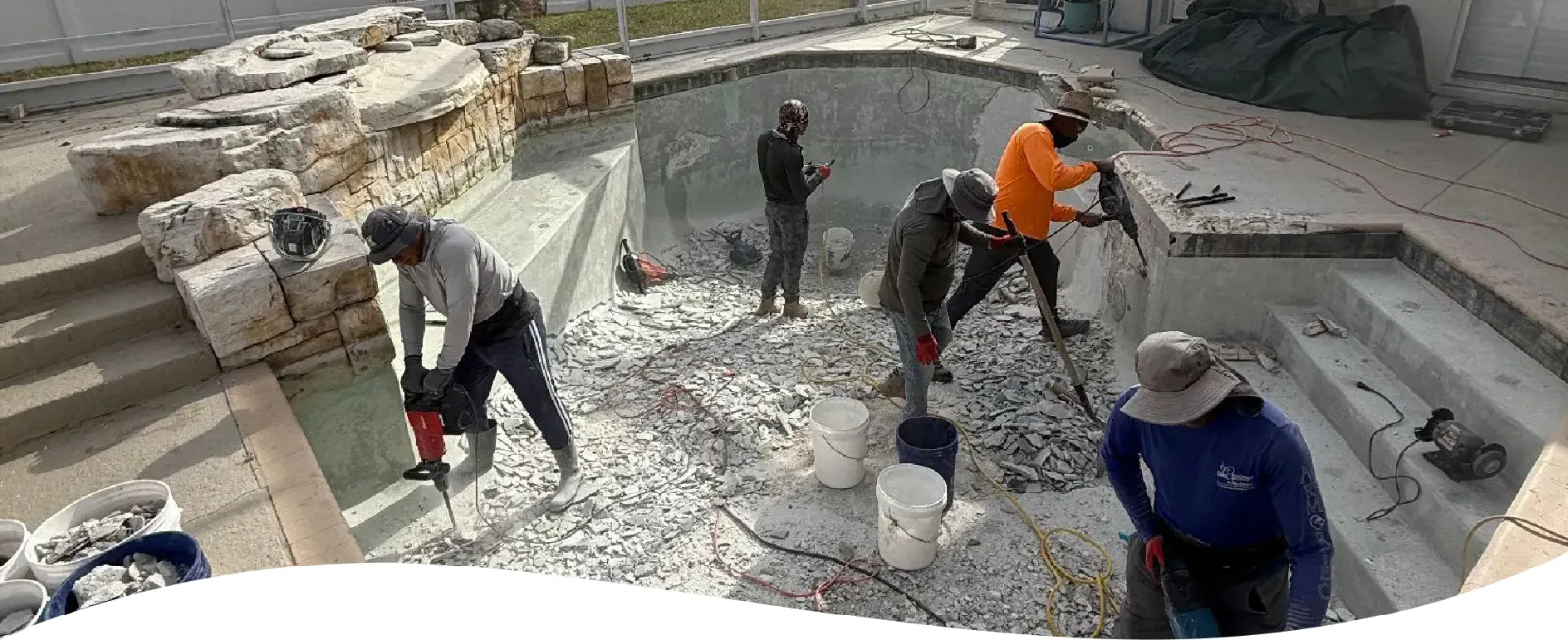 Workers resurfacing an empty pool shell during a remodel.