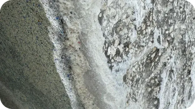 Close-up of cracked, delaminated plaster on a pool wall.