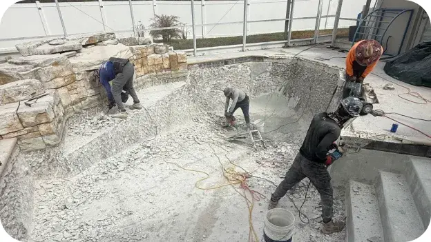 Workers applying new plaster over an existing pool surface.