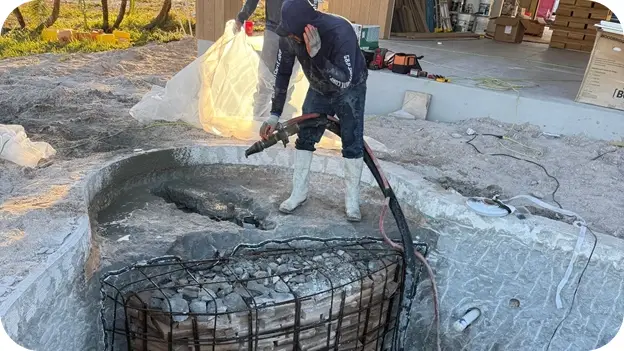 Worker performing torch work at the pool's edge during a structural upgrade.