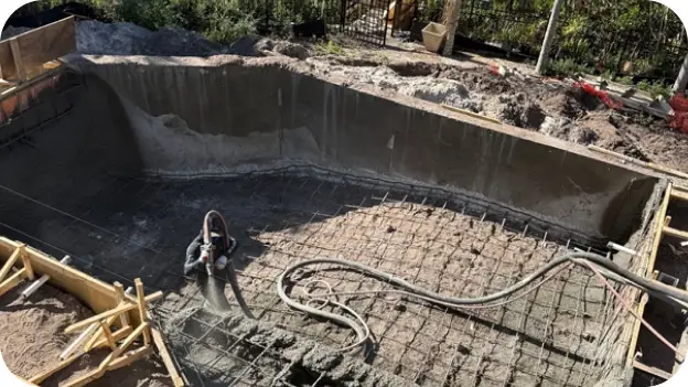 Empty pool shell with a hose and materials during a structural repair.