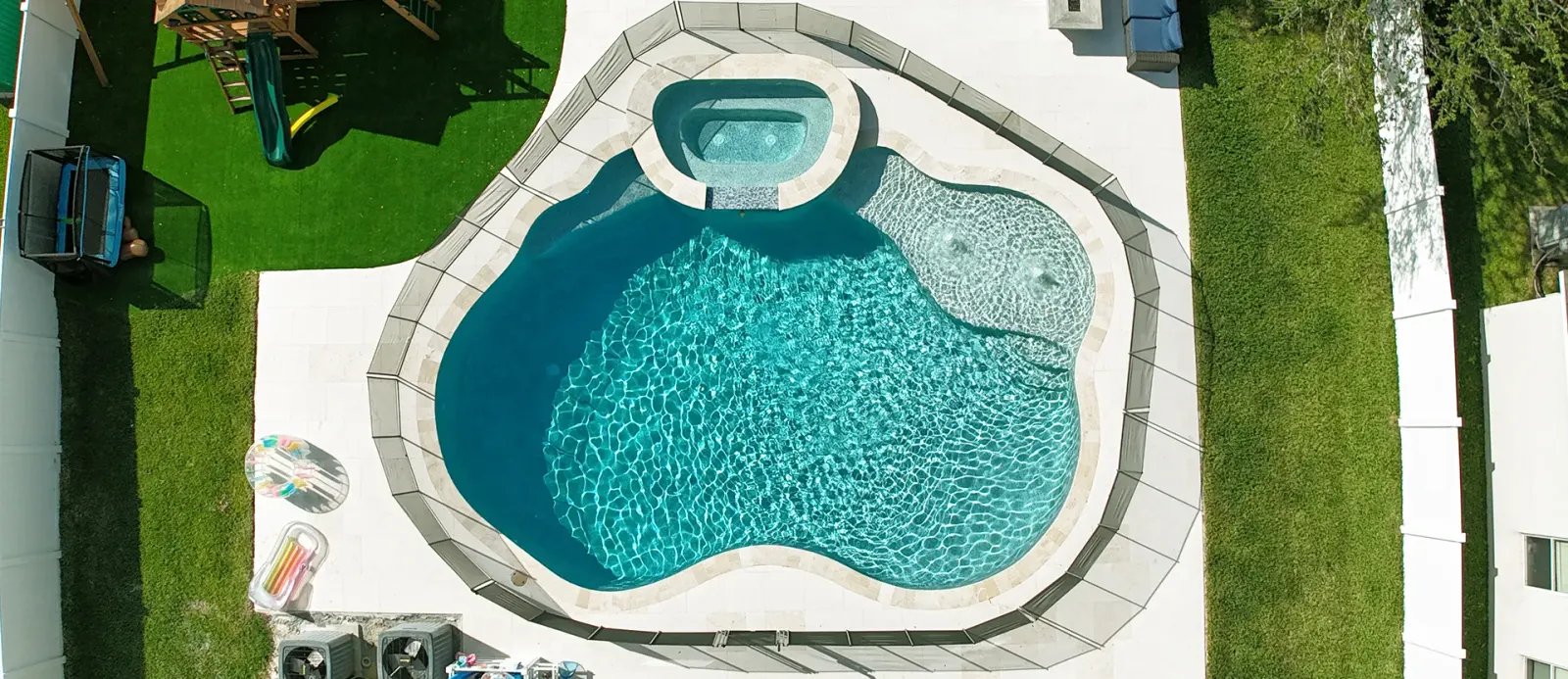 Aerial view of a freeform kidney-shaped pool with a round raised spa.