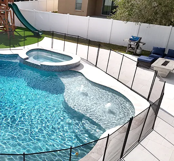 Freeform pool with a round raised spa inside a screened, fenced lanai.