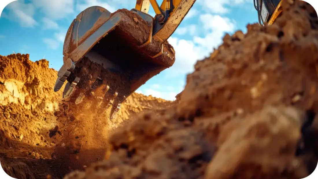 Excavator bucket cutting into soil during pool excavation.