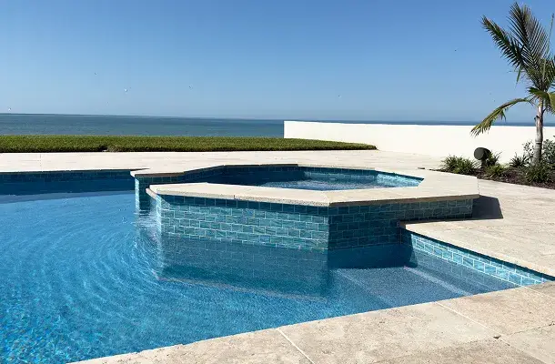Rectangular pool and raised spa with the ocean horizon visible over a low wall.