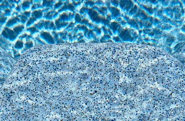 Underwater close-up of the pool's blue pebble aggregate finish.