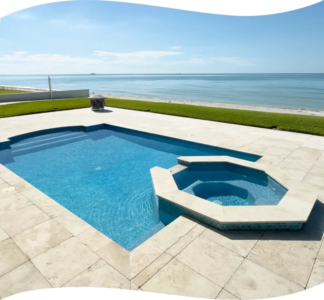 Rectangular pool with an attached raised spa, ocean visible in the distance.