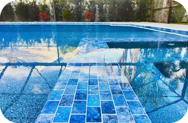Close view of a blue mosaic tile accent band along the pool decking.