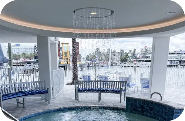 Covered cabana structure over a raised spa with an overhead rain-style water feature.