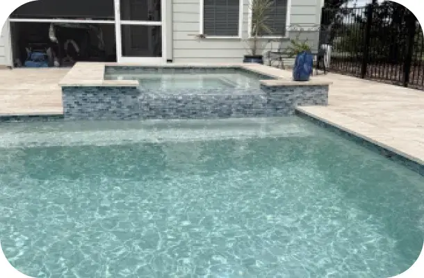 Rectangular pool with an attached raised spa and travertine decking.