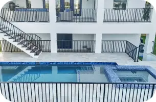 View from the balcony down onto the elevated pool deck, spa, and grass yard below.