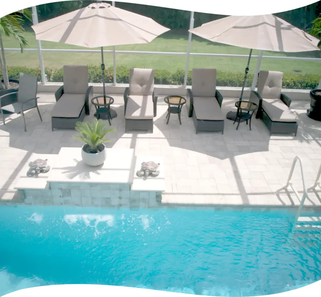 Elevated view of the screened lanai pool deck with lounge chairs and a raised spa.