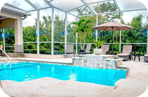 Screened pool enclosure with tropical landscaping and a raised spa water feature.