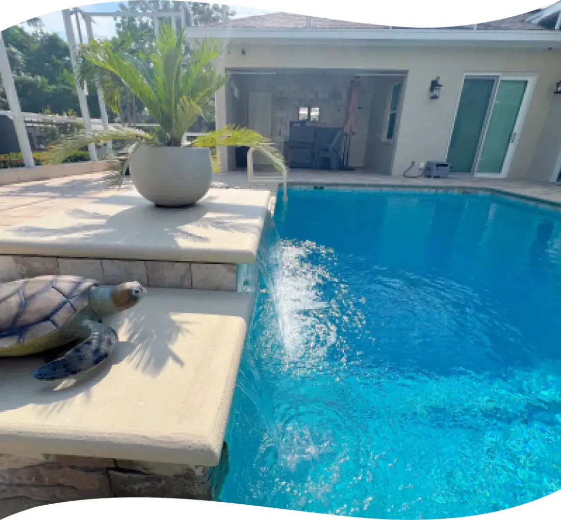 Close view of a decorative turtle statue beside a small water feature spilling into the pool.