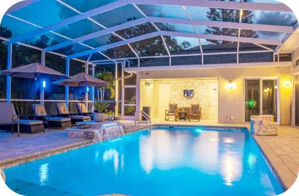 Pool and spa lit at dusk with a shaded lounge area inside the screened enclosure.