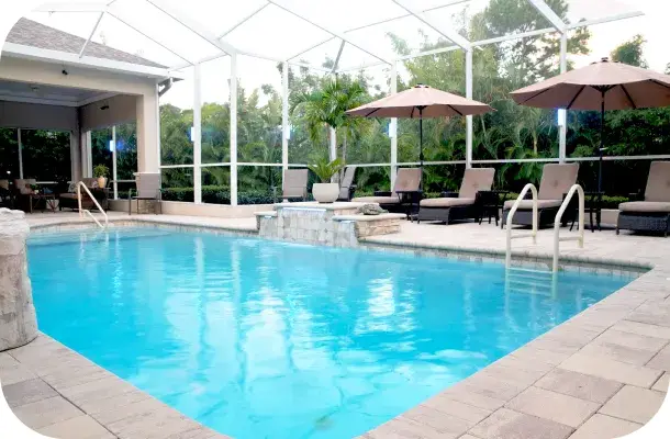 Screened pool with raised spa, tropical plants, and shade umbrellas.