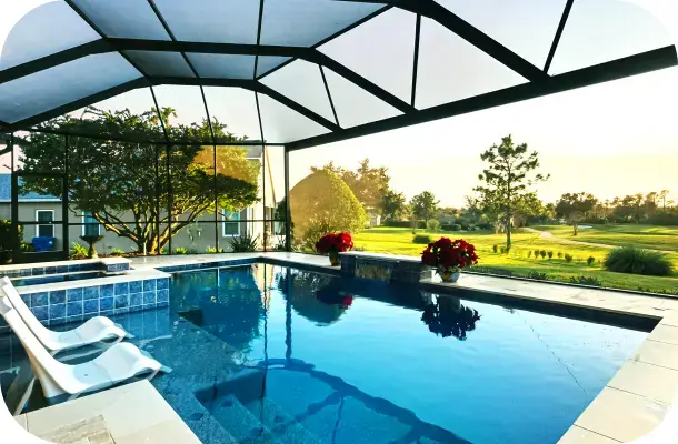 Screened lanai pool with a golf-course view and red flowering planters at dusk.