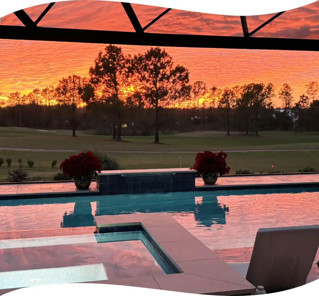 Dramatic sunset sky over the pool, spa, and golf course, planters silhouetted.