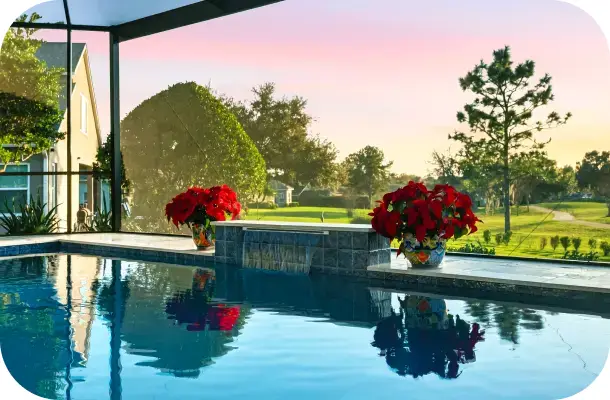 Screened lanai pool and spa with a golf-course view in warm early-evening light.