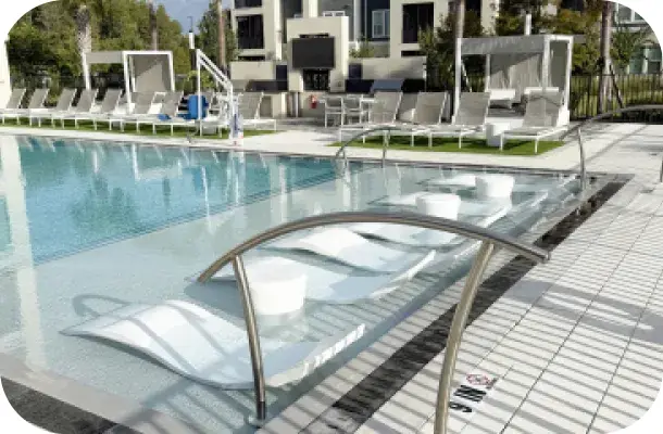 Pool deck with cabana daybeds and canopy shade structures beside the water.