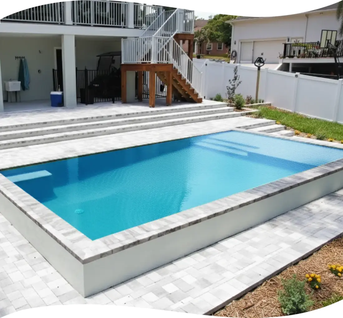 Finished pool and paver decking with wood stairs leading to a raised deck.