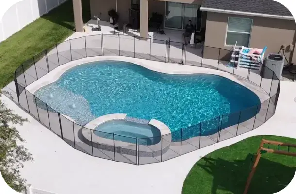 Elevated daytime view of the freeform pool, spa, and playset behind a black safety fence.