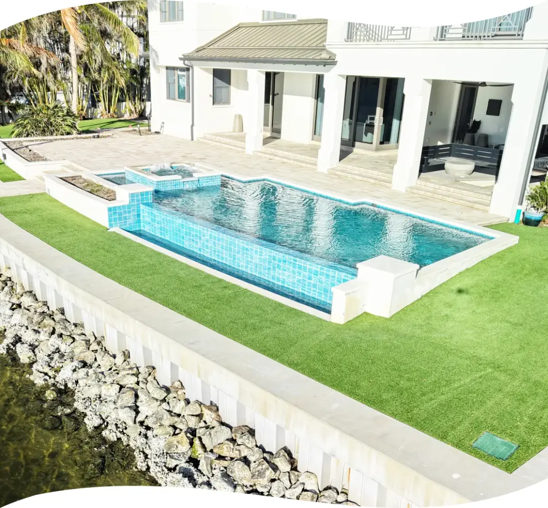 Elevated view of the rectangular pool, raised spa, and tiled accent band beside the home's patio.