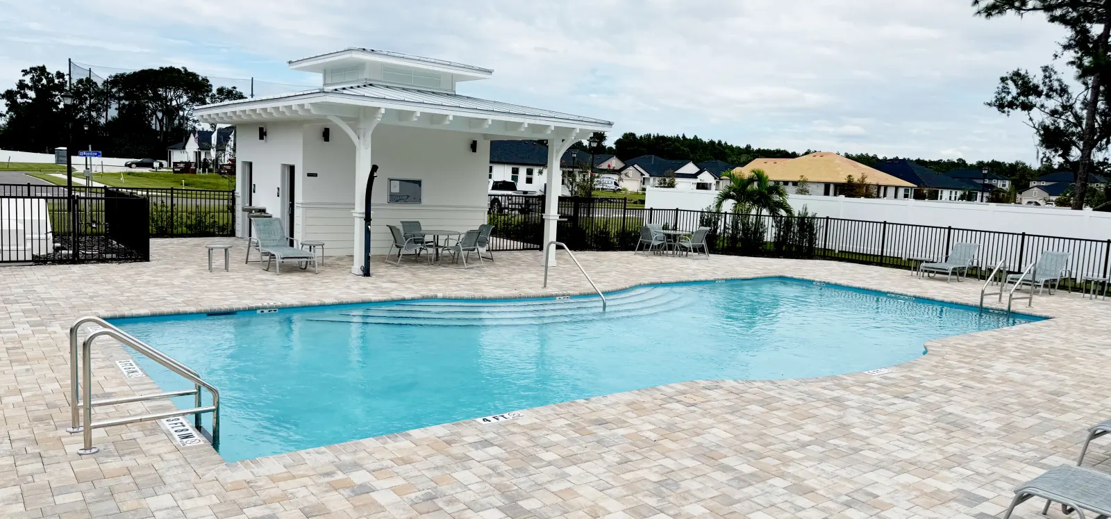 Community clubhouse pool with a shaded pavilion and decorative lattice railing.