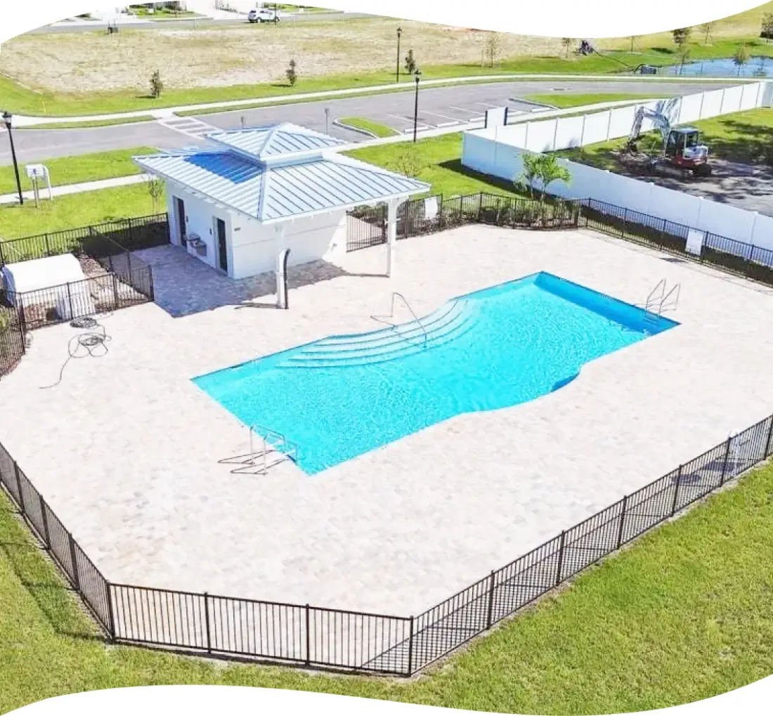 Aerial view of the clubhouse and pool with the parking lot in view.