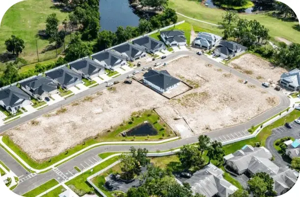 Aerial view of the surrounding development under construction, with roads laid out and homes being built nearby.