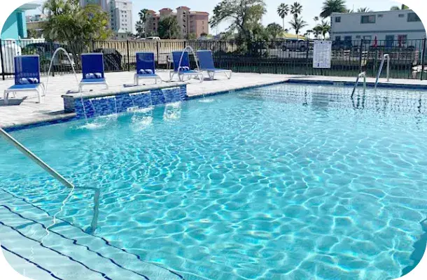 Finished rectangular pool with a tiled waterline band, lounge chairs, and a canal view.