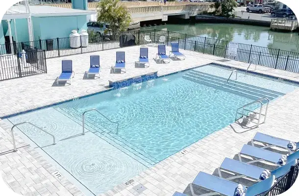 Finished pool with lounge chairs along the canal, building visible behind.