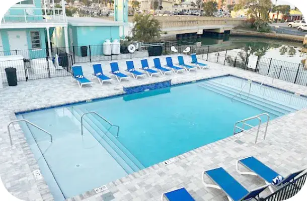 Wide view of the finished pool deck with lounge chairs and the canal beyond.