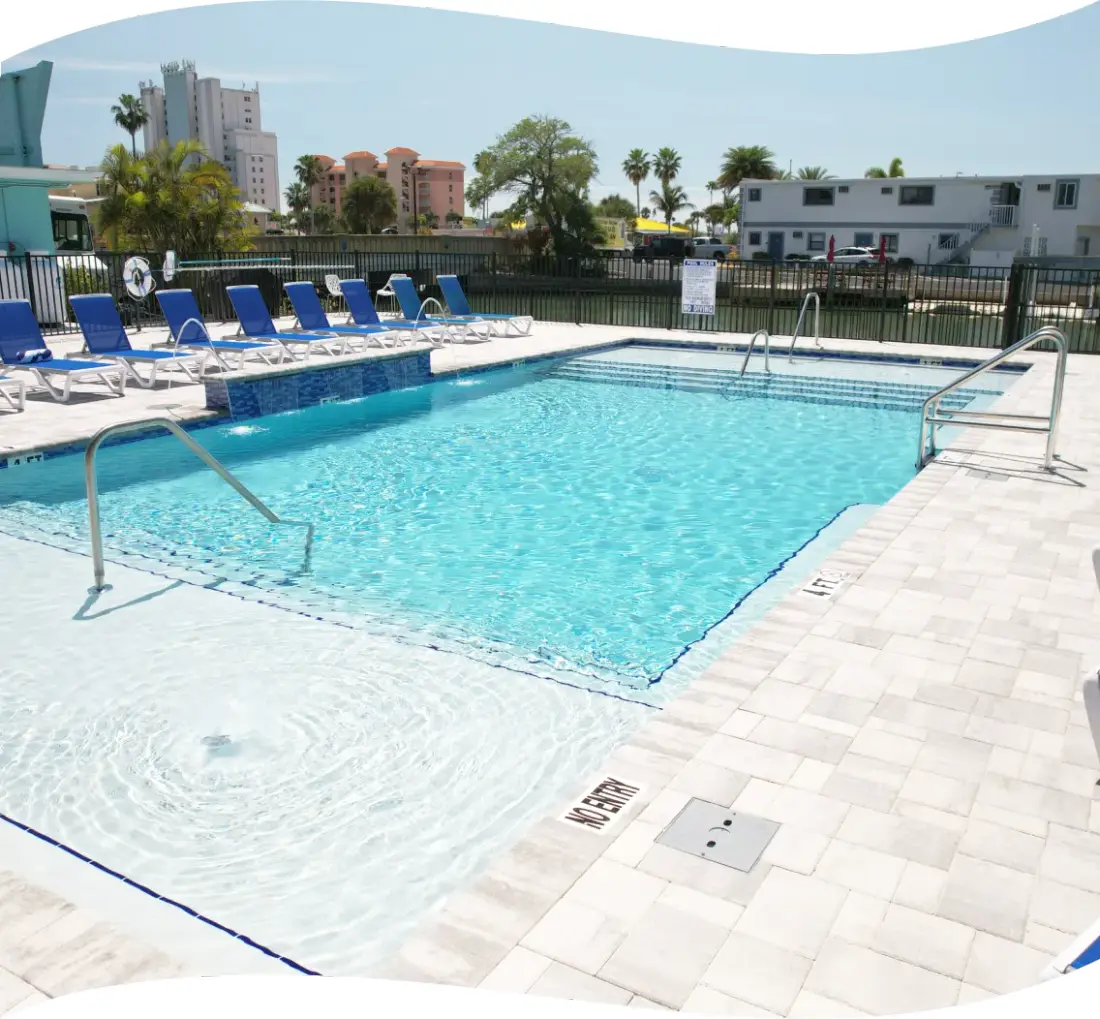 Finished pool with lounge chairs and a canal view beside a low-rise building.