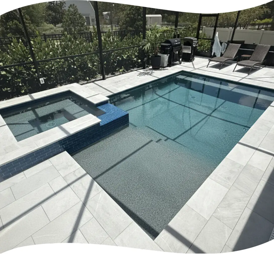 Elevated view of the screened pool and raised spa with trees behind the yard.