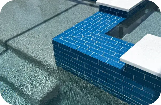 Close view where the spa's blue tile meets the paver decking at the water's edge.