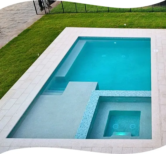 Rectangular in-ground pool with a built-in bench along one wall, bordered by open lawn.
