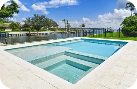 Elevated daytime view of the pool and raised spa beside a canal waterway with a dock.