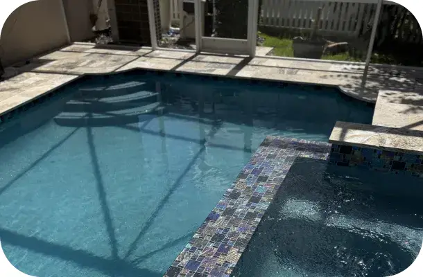 Elevated view of the geometric pool and travertine decking within the screened lanai.