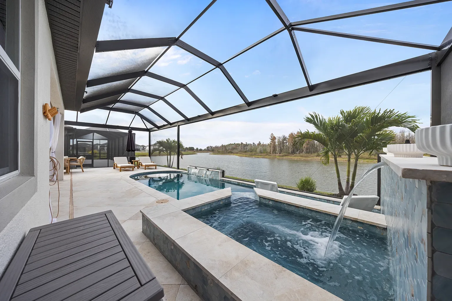 Raised spa spilling through a sheer descent waterfall on a mosaic-tiled wall into the pool below, Wesley Chapel, Florida.