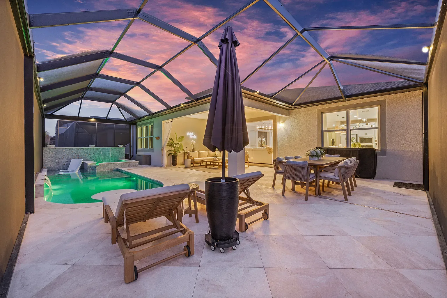 Pool deck at dusk with the pool lit green and warm light from the house behind it, Wesley Chapel, Florida.