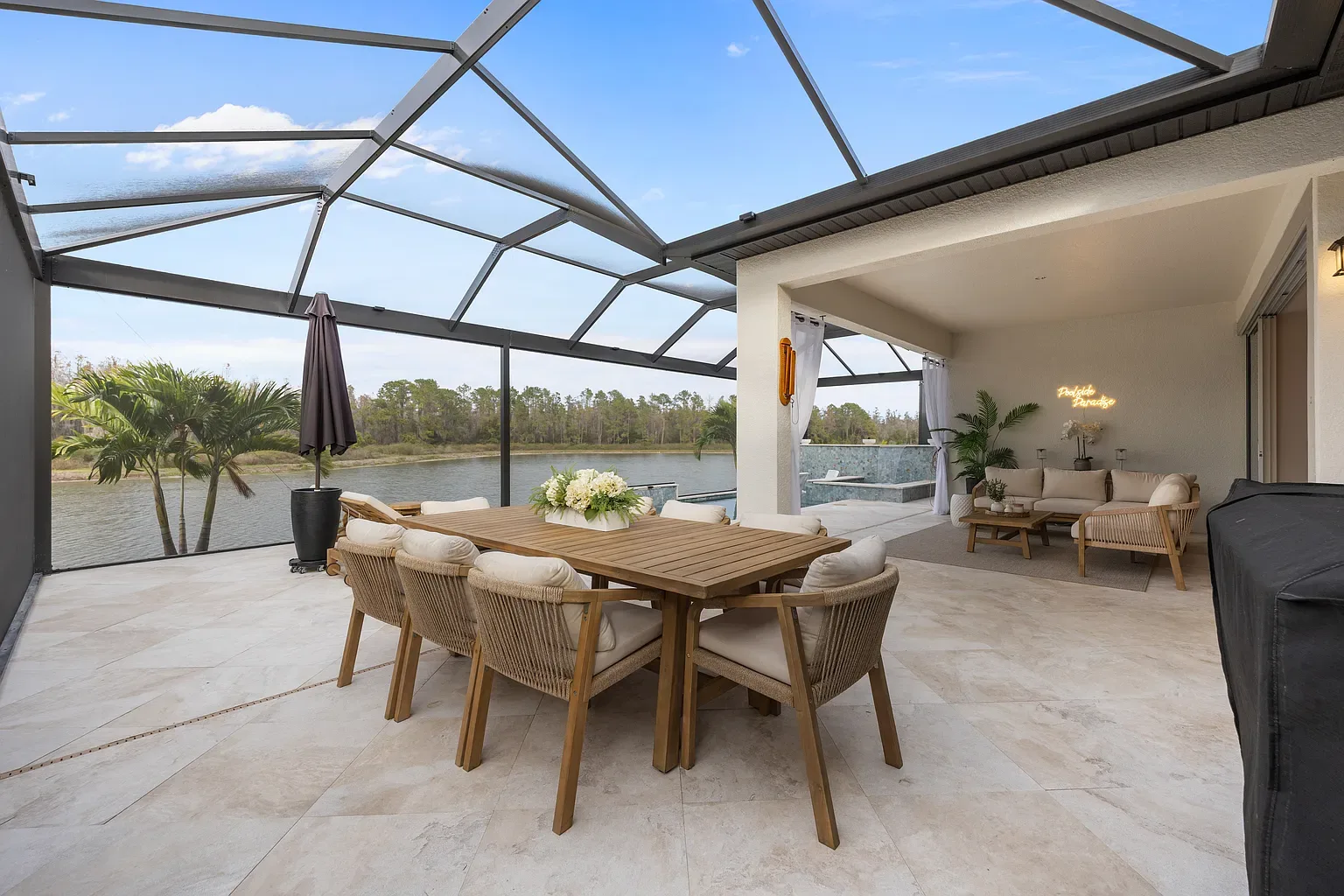 Outdoor dining table for six on a travertine pool deck inside a screened lanai overlooking a lake, Wesley Chapel, Florida.